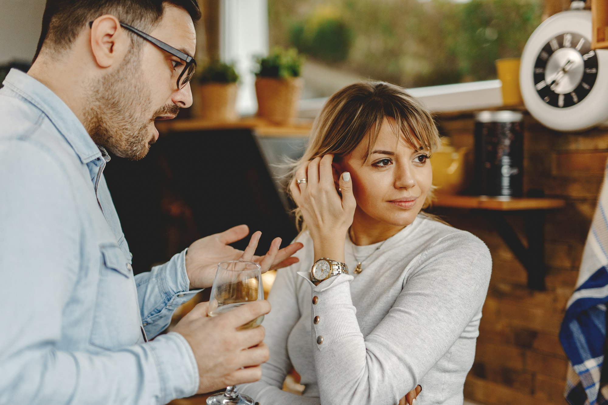 Pensive woman ignoring her boyfriend while he is talking to her in the kitchen.